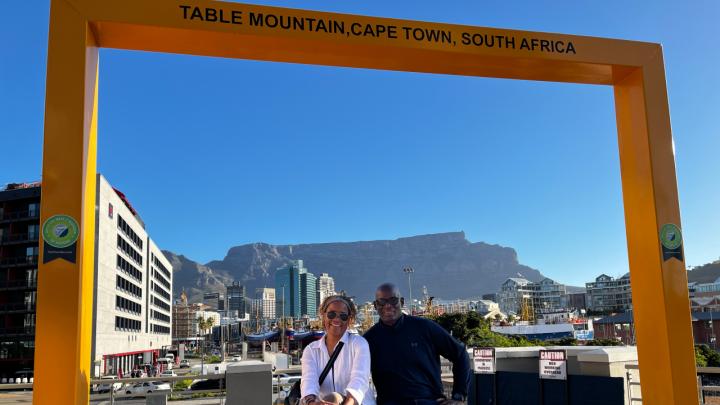 Man and woman sitting on table mountain inscription with Table Mountain in background