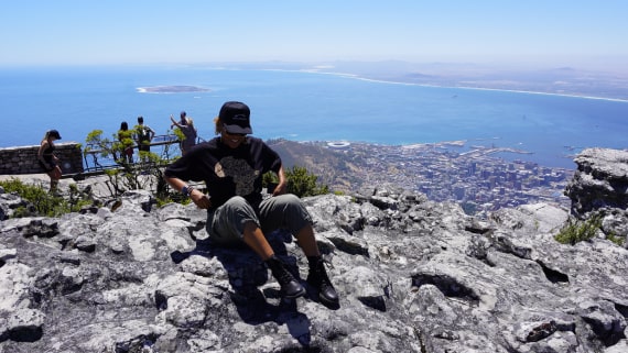 Woman sitting on table mountain with Cape Town in the background