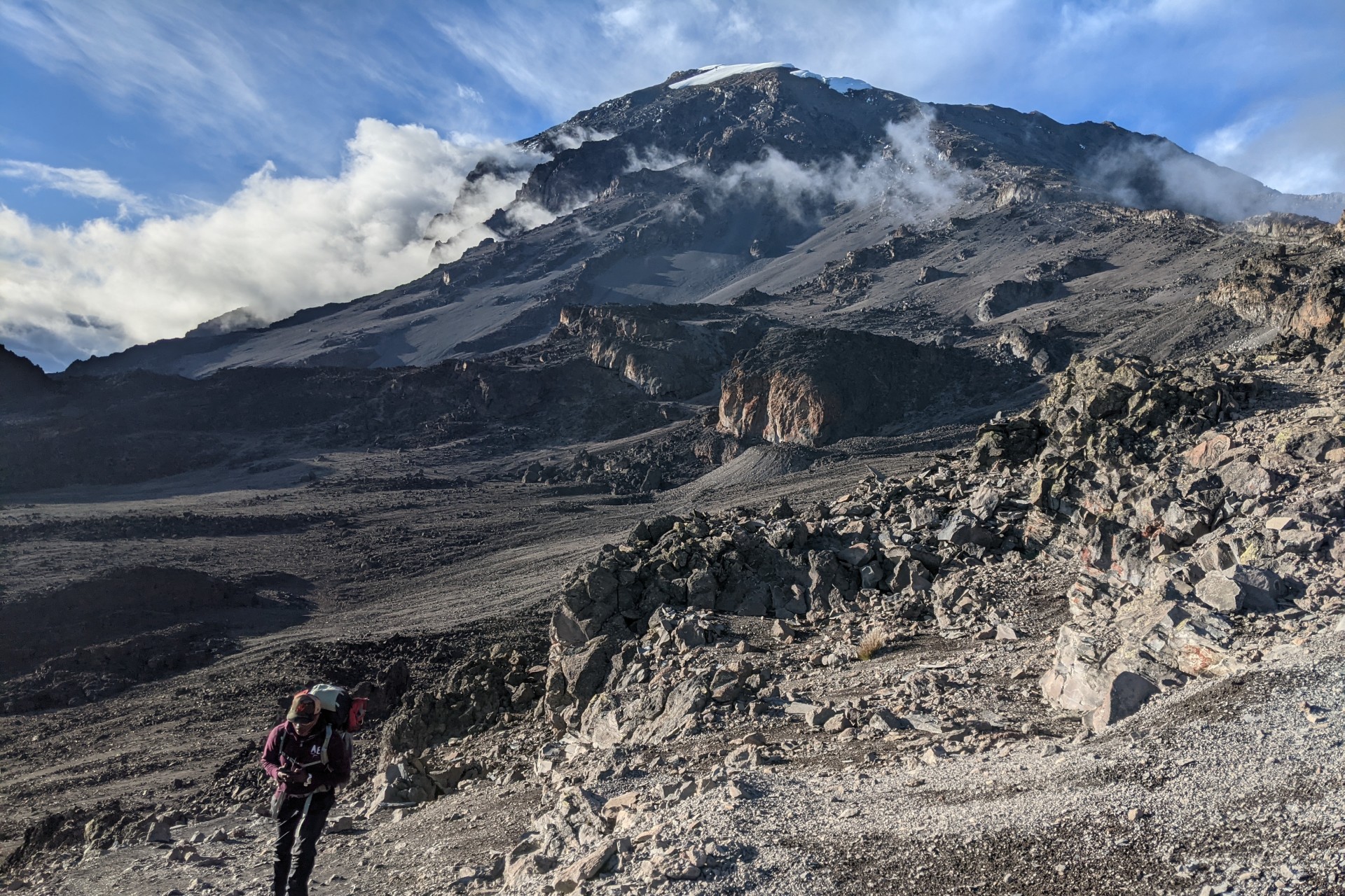 A hiker walking away the rocky landscape of mount Kilimanjaro