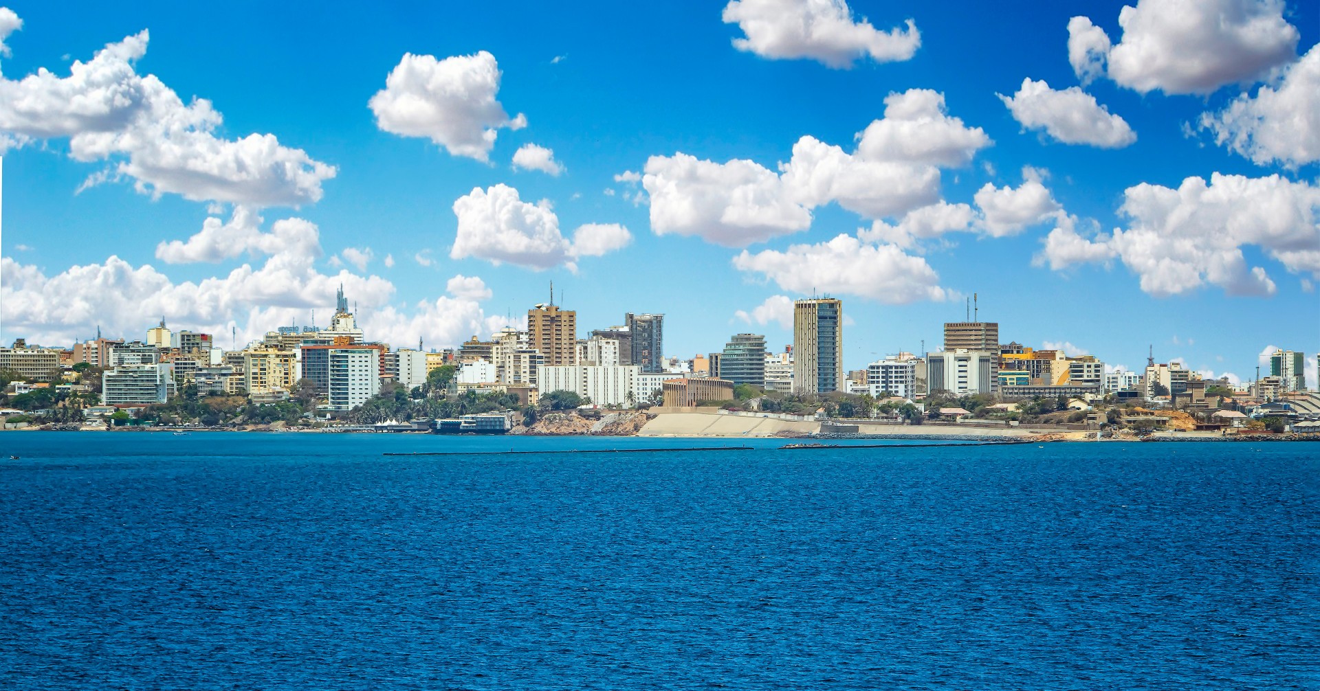 View of the Senegal capital of Dakar, Africa. It is a city panorama taken from a boat. There are large modern buildings and a blue sky with clouds.