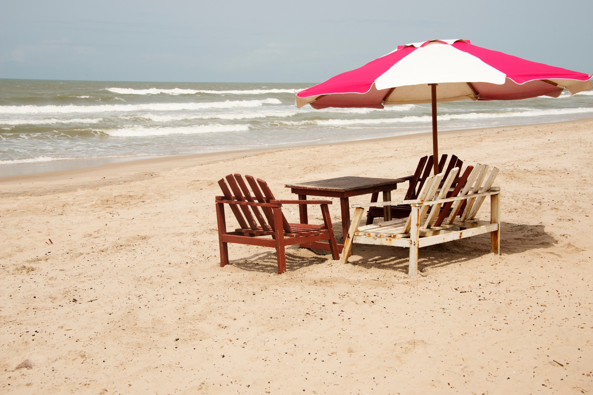 A picture of beach chairs, a table and a beach umbrella