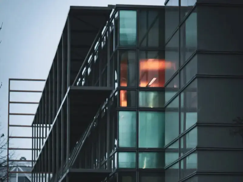 A contemporary glass building with illuminated interiors, showcasing modern architecture.