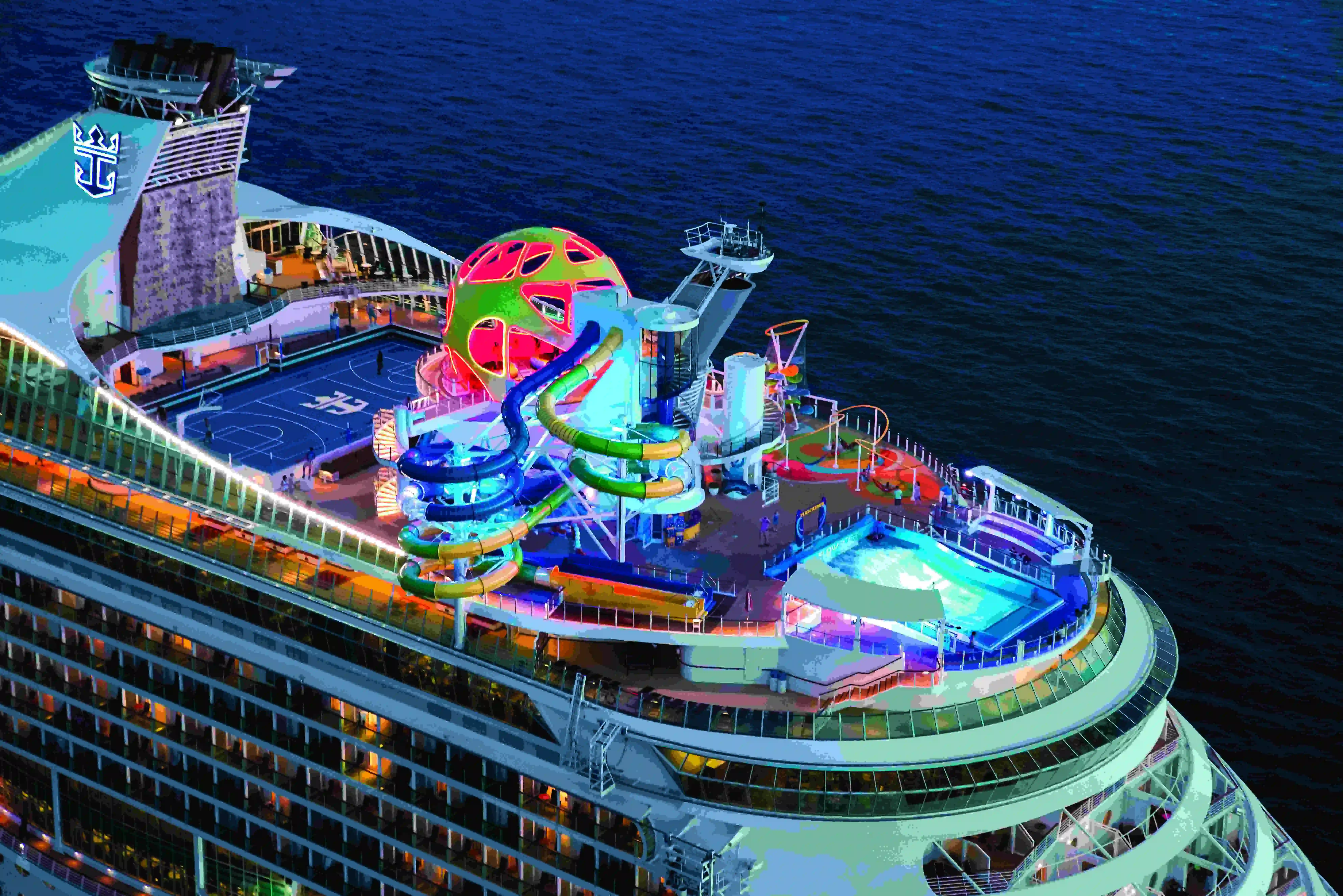 Aerial view of a cruise ship's colorful top decks, pools and water slides at sea.
