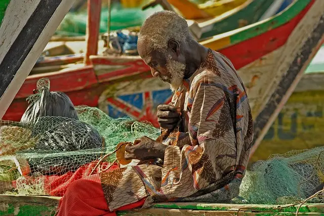 Ghanaian fisherman repairing a net for a destination guide
