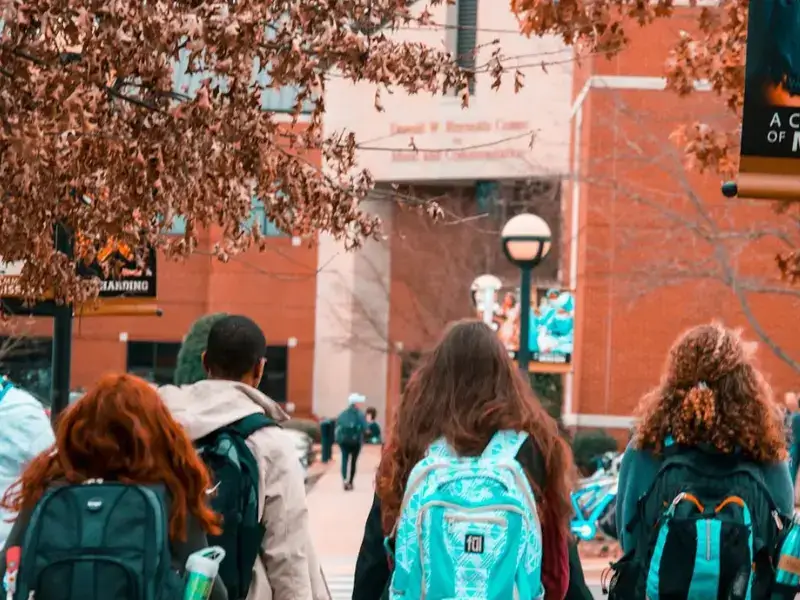 A group of students with backpacks walking together across a university campus.