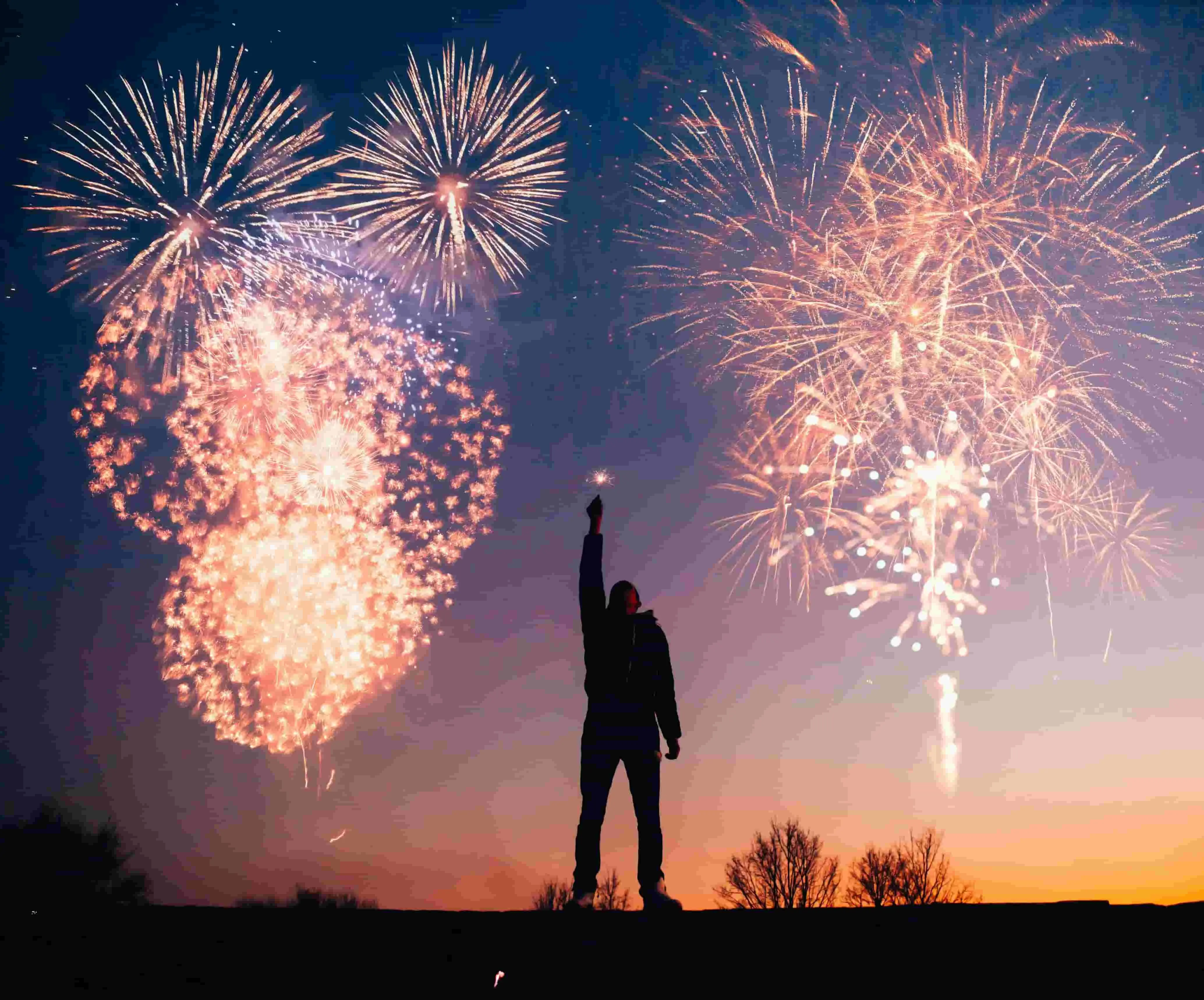 A person silhouetted by fireworks for a destination guide