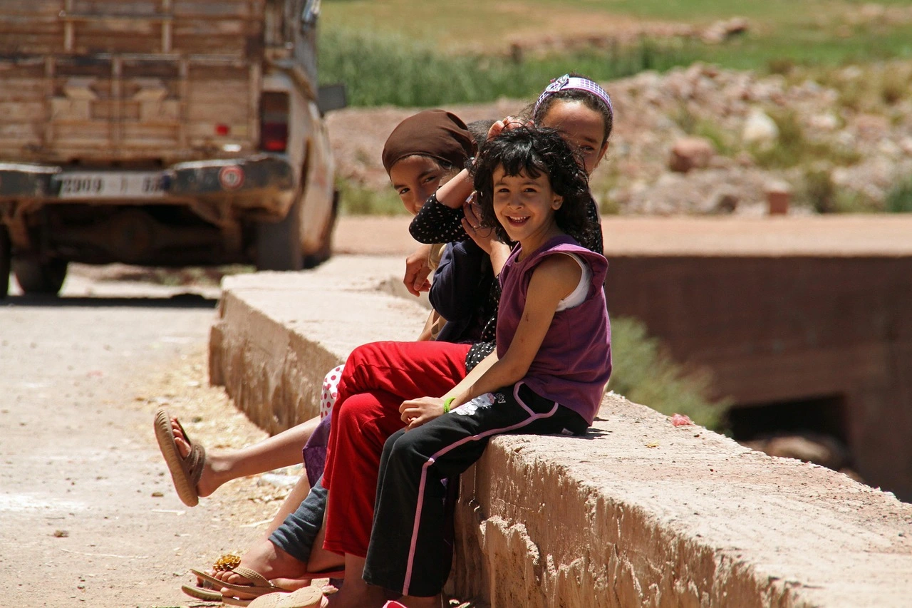 Three smiling Moroccan children sitting
