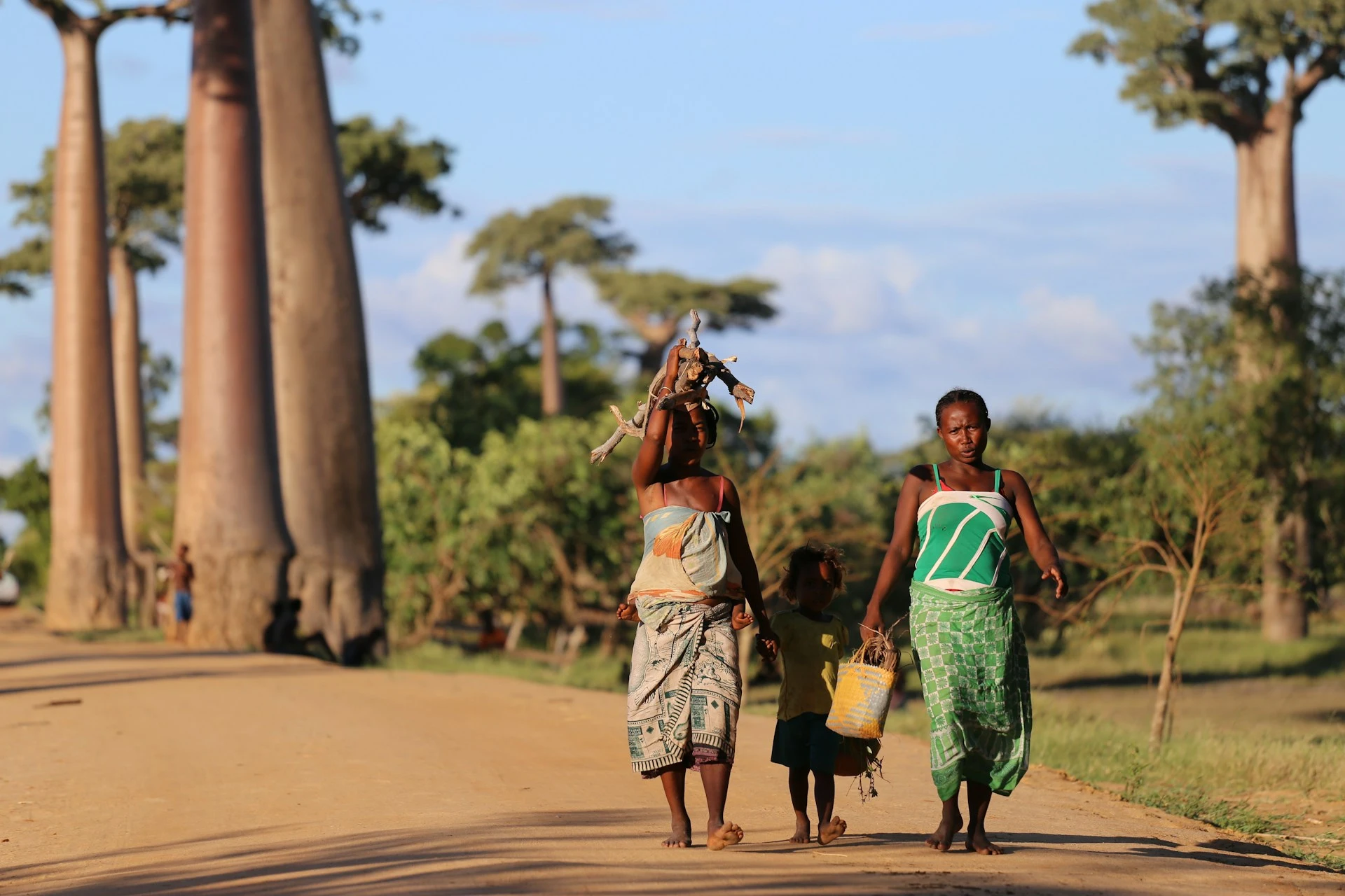Two women and a child walk down a dirt road in Madagascar featured
