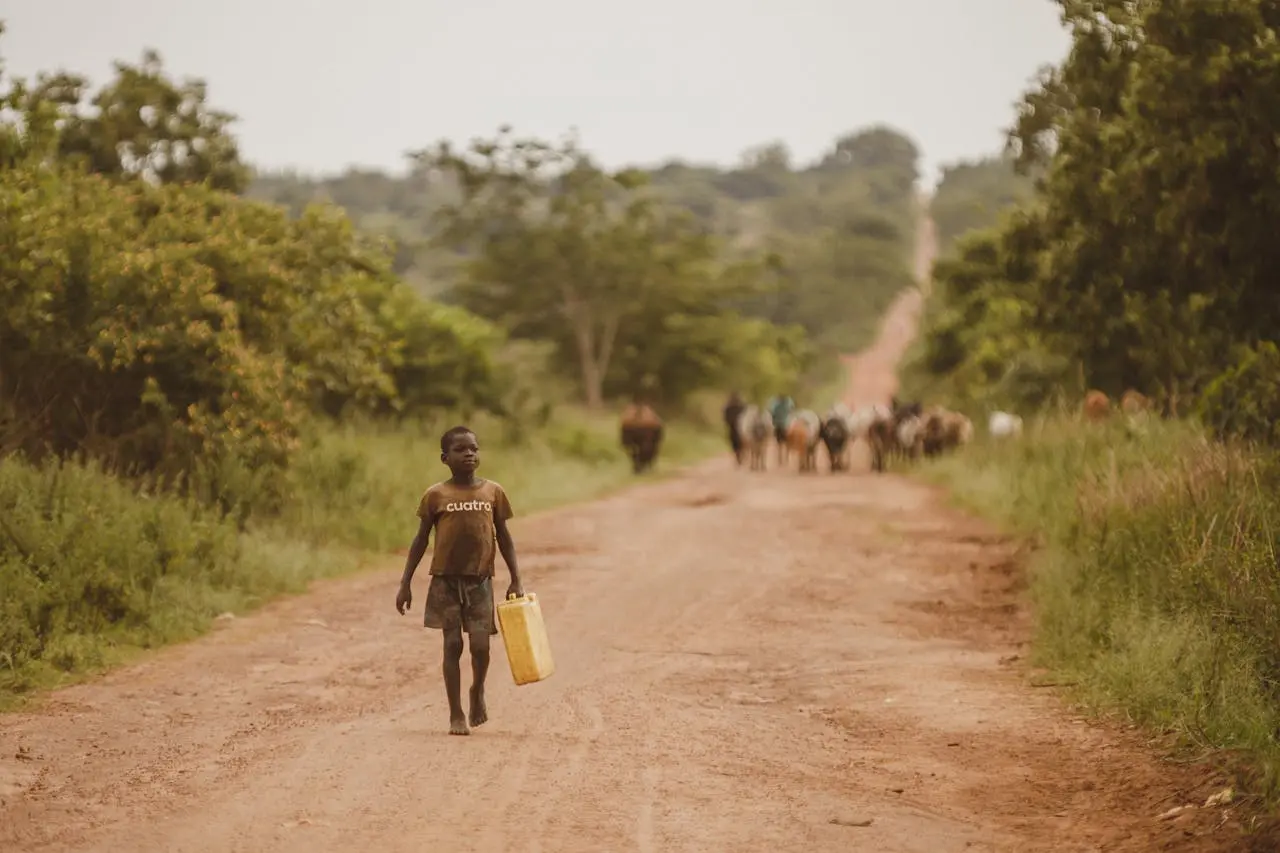 Young boy carrying a yellow jerrycan in Uganda featured