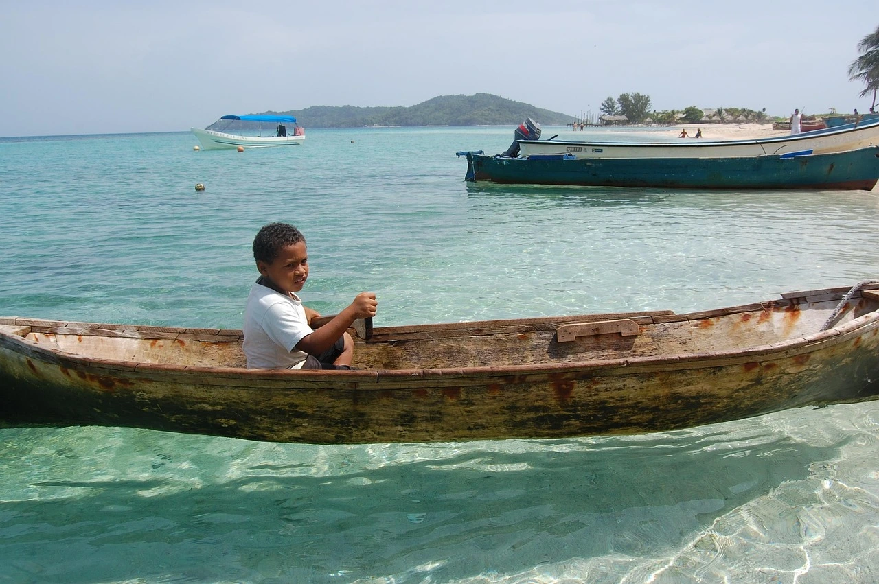 A young boy in a wooden canoe on clear turquoise water