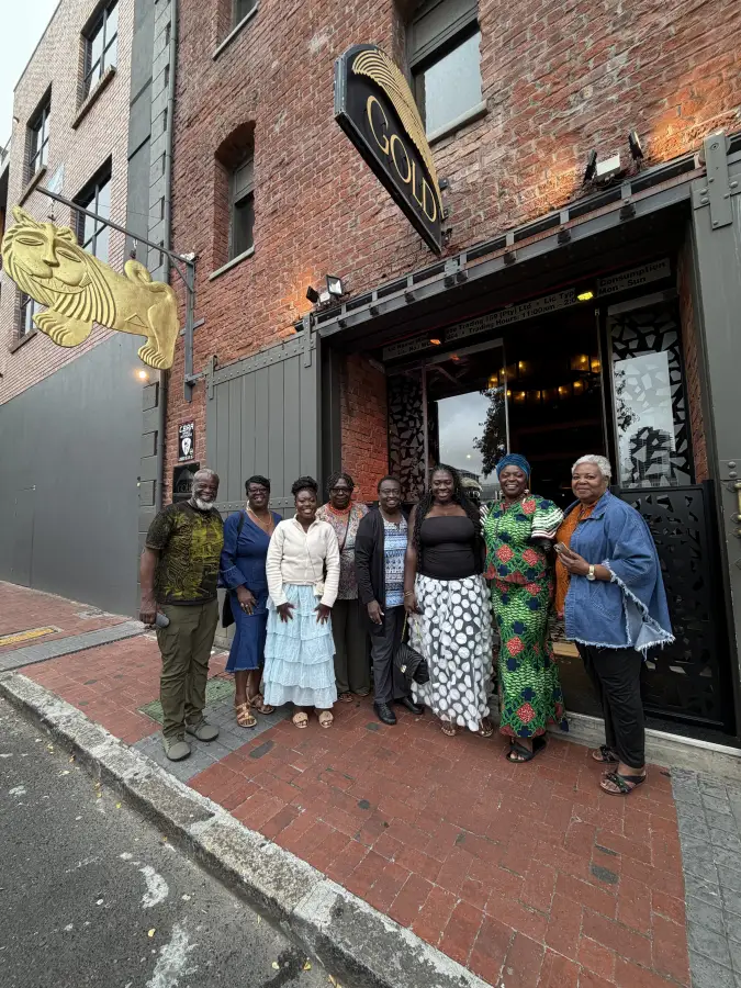 Group of eight professionals posing outside Gold Restaurant entrance for eat-mea-2026 dining event in Cape Town.