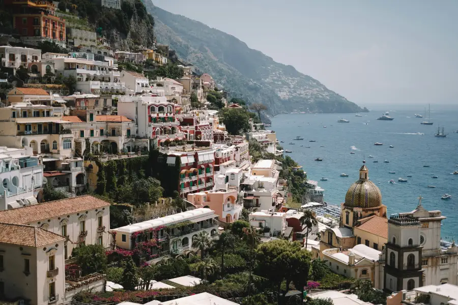 Colorful cliffside buildings of Positano overlooking the Tyrrhenian Sea with yachts anchored; ideal for group cruises alon...