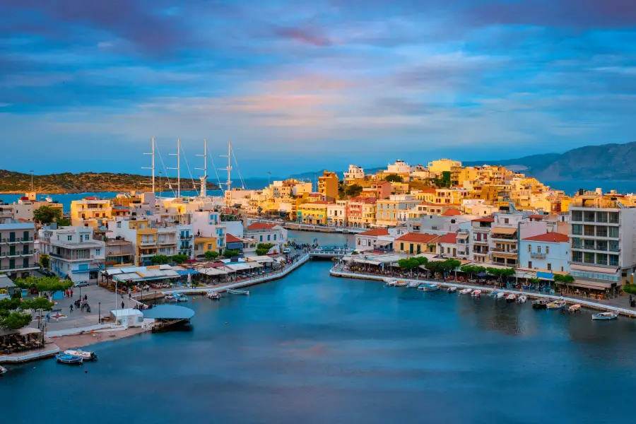 Colorful Mediterranean harbor town at sunset with sailboats docked; ideal backdrop for group cruises and corporate travel...