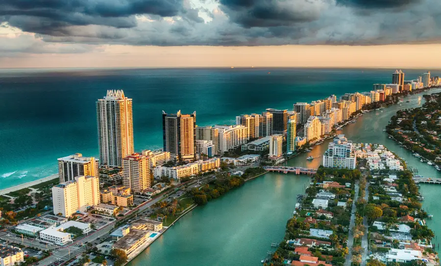 Aerial sunset view of Miami Florida's South Beach skyline with turquoise Atlantic Ocean and Intracoastal Waterway below stretching to the horizon