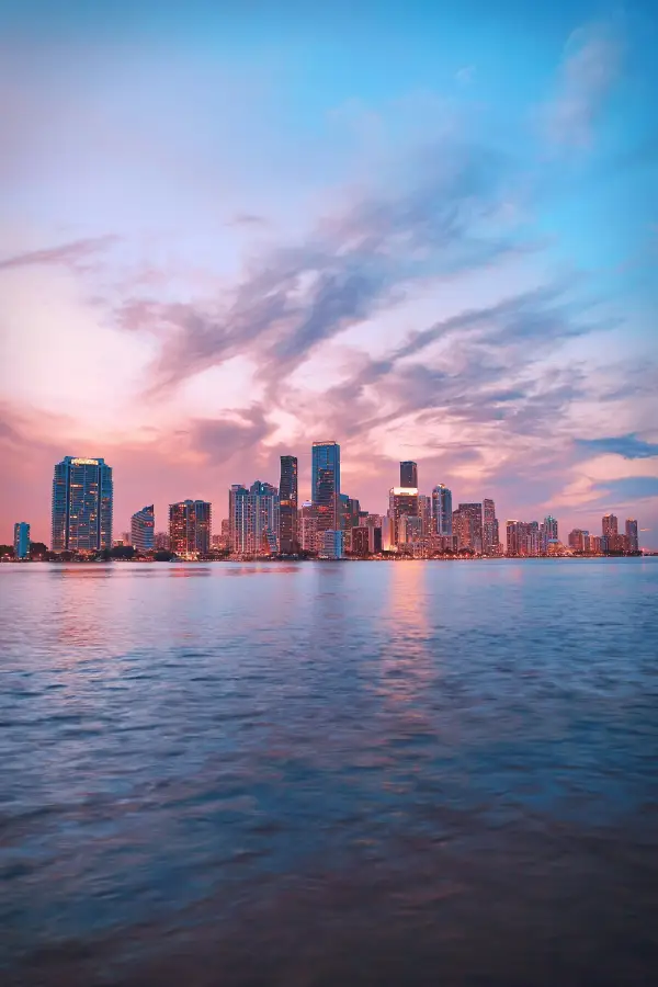 Miami Florida downtown skyline at sunset reflected over Biscayne Bay with dramatic pink and blue clouds