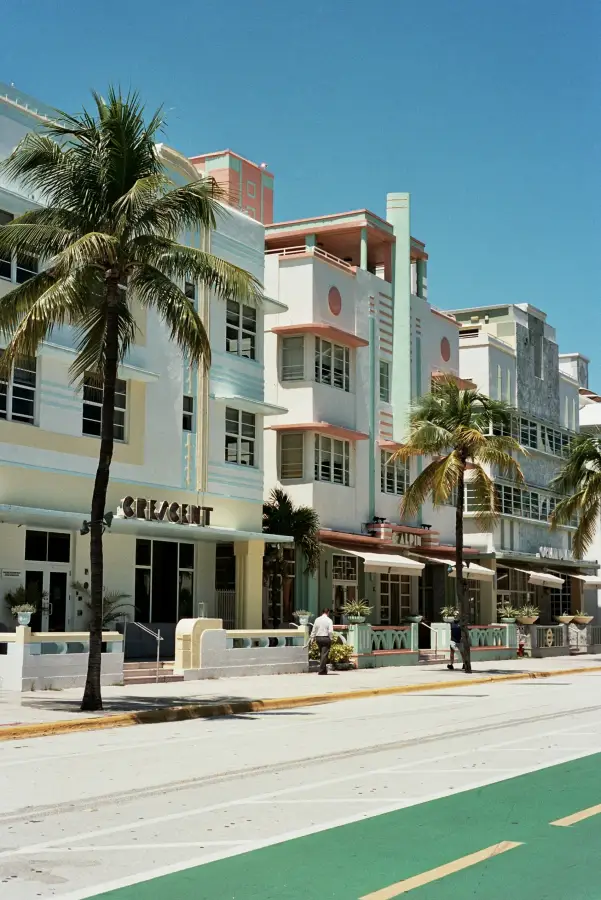 Art Deco hotels including the Crescent and Alpin line Ocean Drive in Miami Florida; flanked by palm trees under a clear bl...