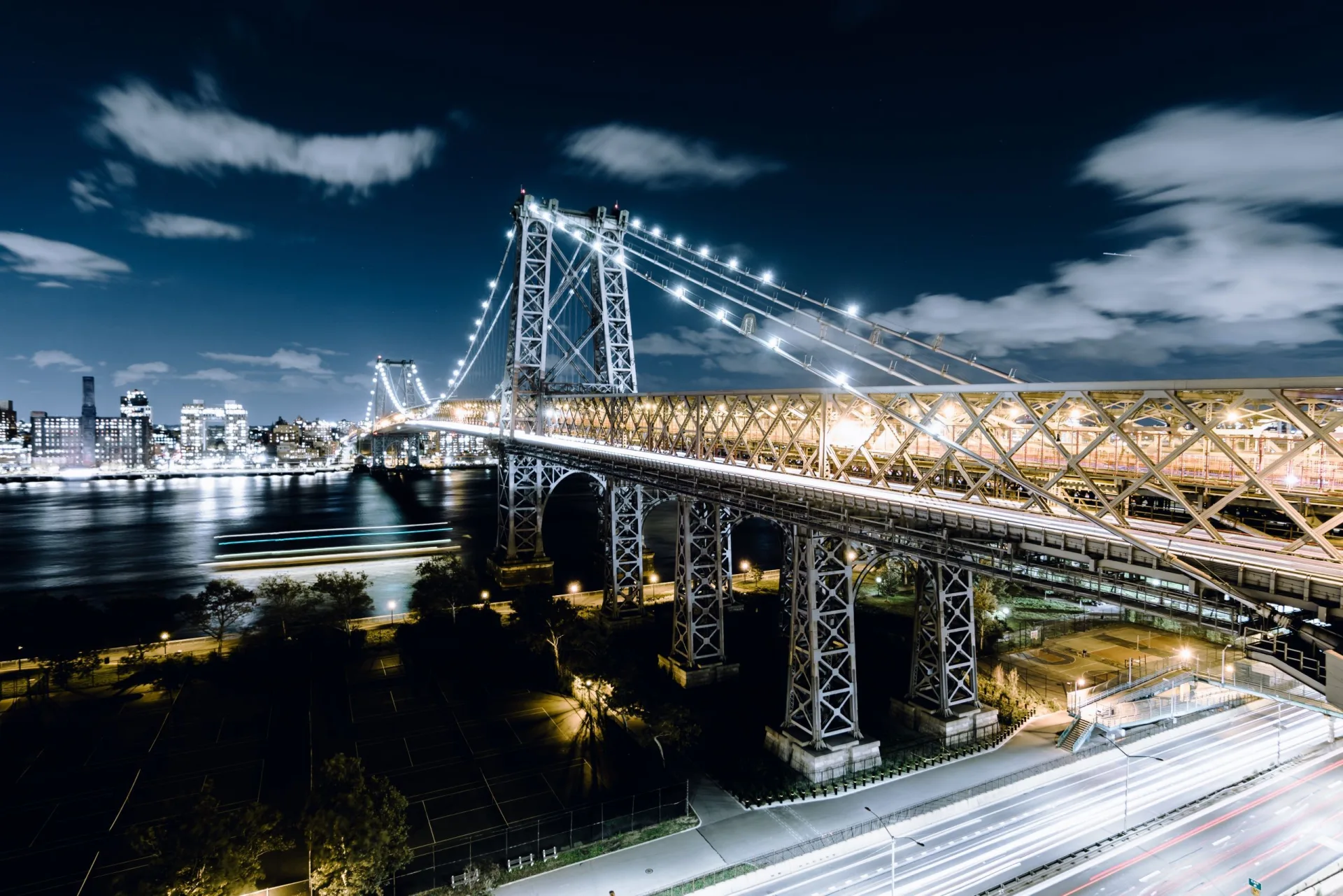 Queensboro Bridge spanning the East River in New York New York with city skyline and light trails from traffic below