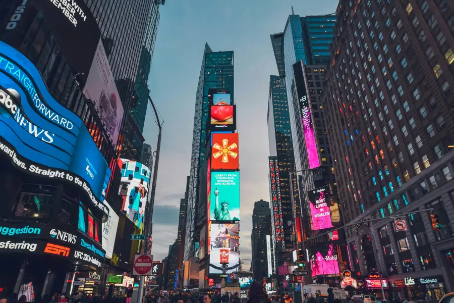 Glowing digital billboards and skyscrapers line Times Square in New York New York at dusk with crowds below