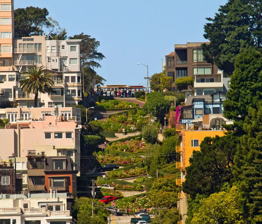 Iconic winding Lombard Street in San Francisco; CA; lined with colorful flowers; historic buildings; and a cable car at th...