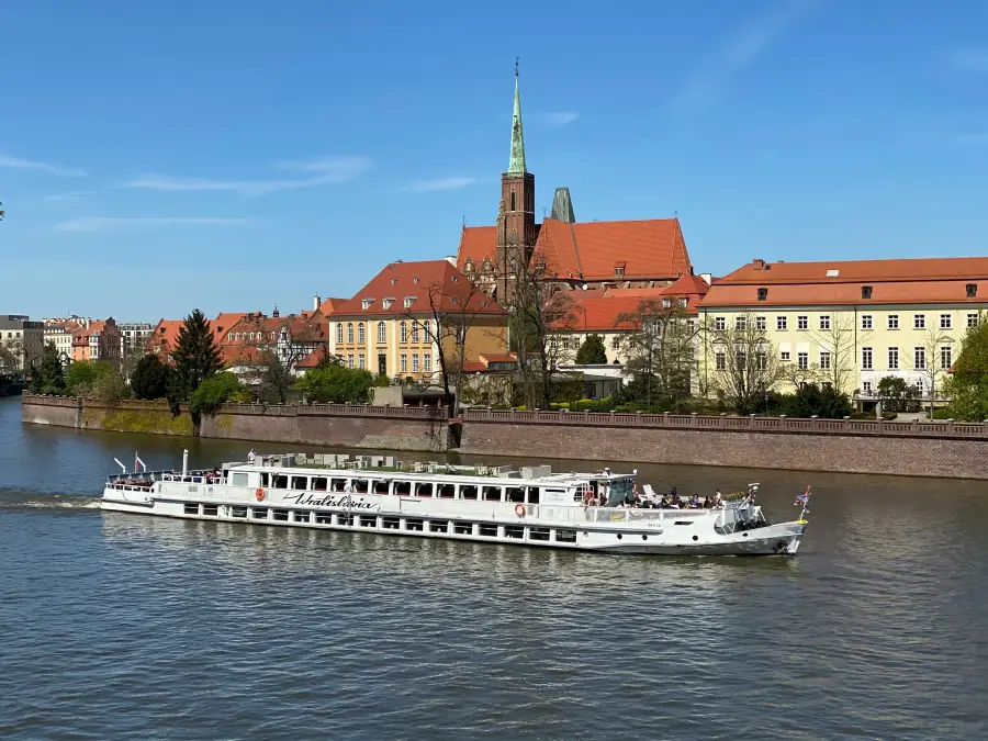 Wratislavia cruise boat sailing the Oder River in Wrocław; Poland; with Collegiate Church of the Holy Cross in background.