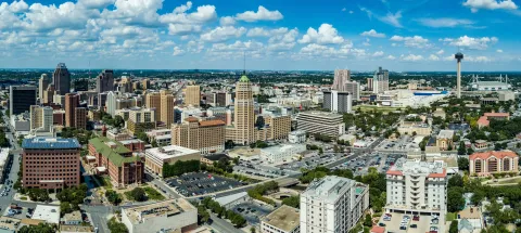 Aerial panoramic view of San Antonio Texas downtown skyline with Tower of the Americas and historic buildings under blue sky