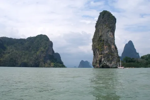 Limestone karst islands rising from the calm green water of Phang Nga Bay in southern Thailand.