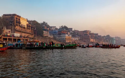 Wooden boats moored below the stone ghats and riverfront buildings of Varanasi on the Ganges.