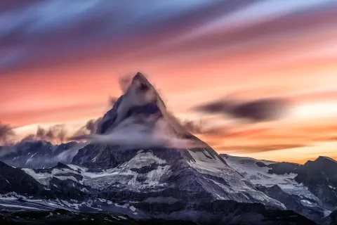 The pyramid peak of the Matterhorn in Switzerland at sunset, cloud streaming from its summit ridge