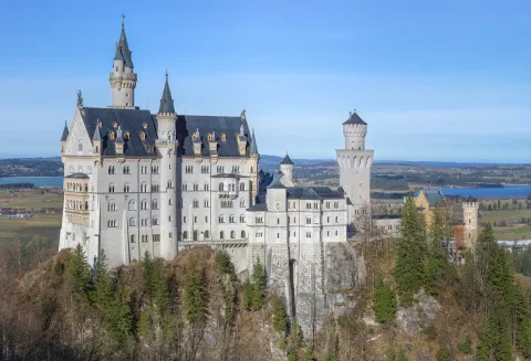 Neuschwanstein Castle in Bavaria, its pale towers rising from a wooded ridge above the Alpine foothills