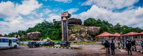 Visitors and a tour coach at the foot of Olumo Rock in Abeokuta, Ogun State, the visitor lift tower on the outcrop.