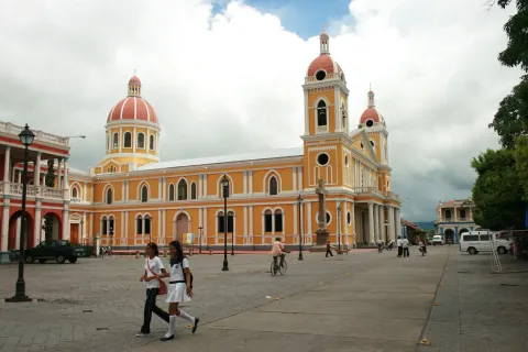 The ochre and white bell towers of the cathedral at Granada in Nicaragua above the square, people in the foreground
