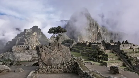 The stone terraces and walls of Machu Picchu in Peru emerging from mist, the peak behind half hidden in cloud
