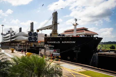 A cargo ship in the Miraflores Locks on the Panama Canal, held between the lock walls with the towing locomotives alongside