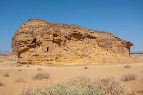A Nabataean tomb carved into a sandstone outcrop at Hegra near AlUla, Saudi Arabia, its facade cut from the living rock.