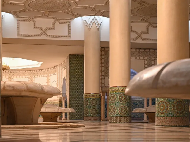 Rows of painted and tiled columns supporting horseshoe arches inside a Moroccan prayer hall.