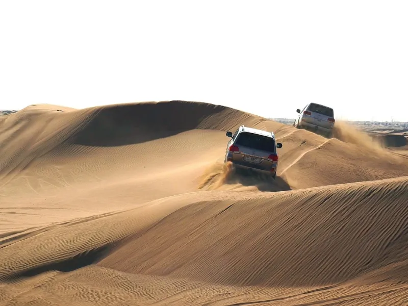 A vehicle cresting a steep sand dune in the desert outside Dubai.