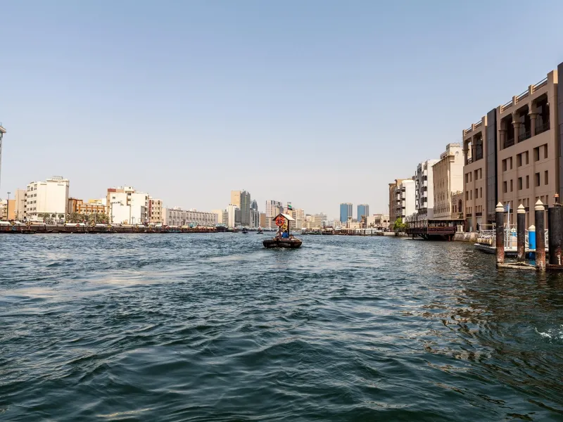 Dubai Creek with the old quarter along the waterfront and boats crossing the channel.