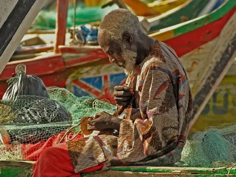 Ghanaian fisherman repairing a net for a destination guide