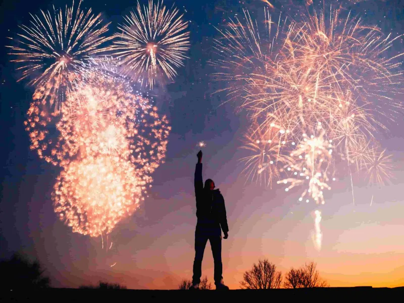 A person silhouetted by fireworks for a destination guide
