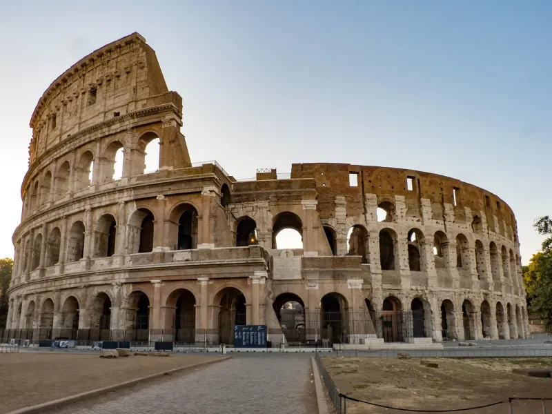 The Colosseum in Rome in early light, its arcaded tiers rising above an empty forecourt.