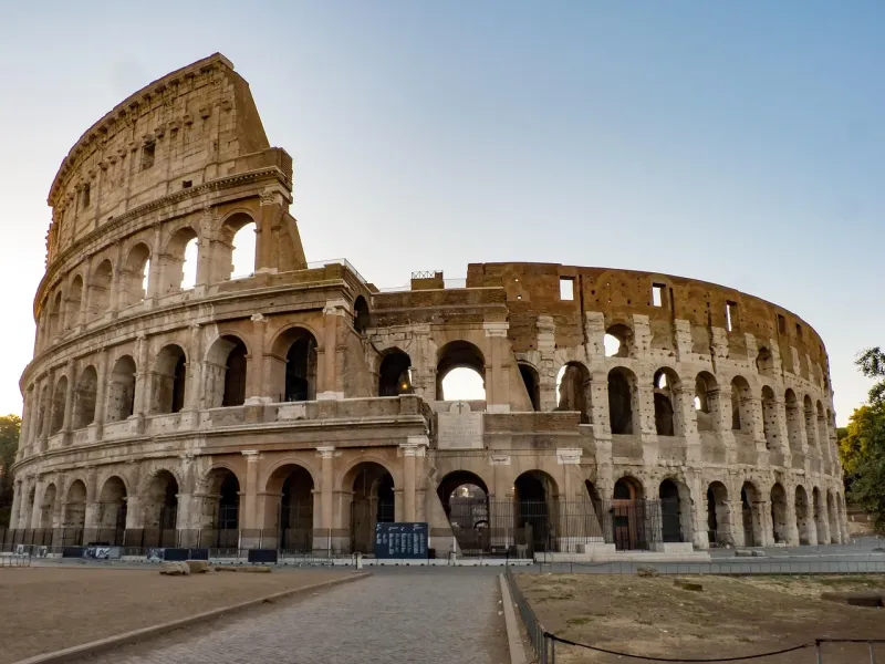 The Colosseum in Rome, its tiers of arches lit by low sun