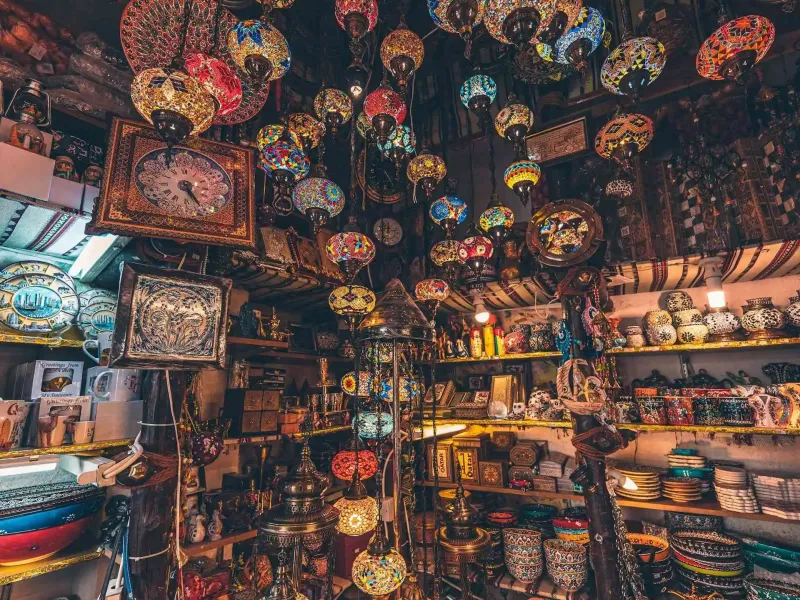 Carpets, textiles and lanterns crowding a covered alley in a Qatari souq.