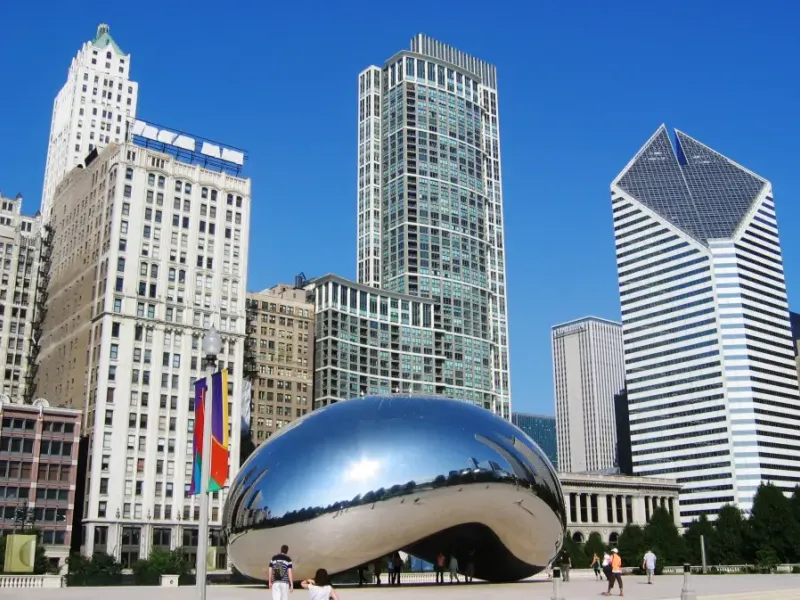 Cloud Gate sculpture reflecting Chicago Illinois skyline and skyscrapers in Millennium Park on a clear blue day