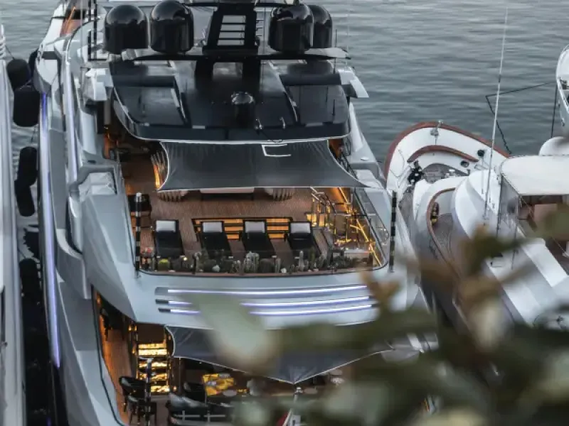 Aerial view of a luxury superyacht docked in a marina at dusk; with illuminated decks and cruise amenities visible.