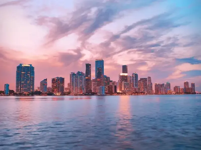 Miami Florida downtown skyline at sunset reflected over Biscayne Bay with dramatic pink and blue clouds