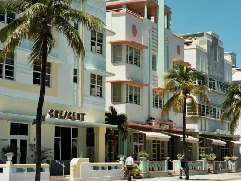 Art Deco hotels including the Crescent and Alpin line Ocean Drive in Miami Florida; flanked by palm trees under a clear bl