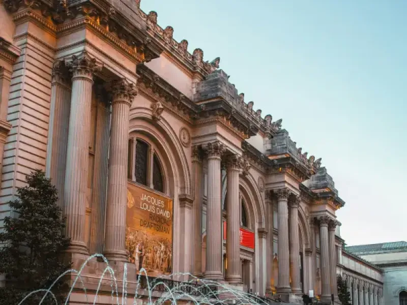 Metropolitan Museum of Art facade in New York New York with fountain at David H. Koch Plaza at dusk and Jacques-Louis David exhibition banner