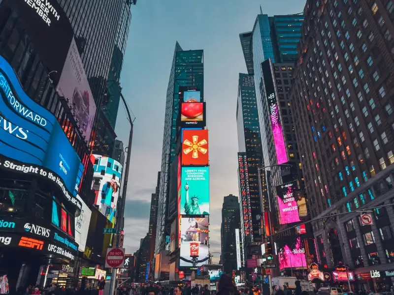 Glowing digital billboards and skyscrapers line Times Square in New York New York at dusk with crowds below