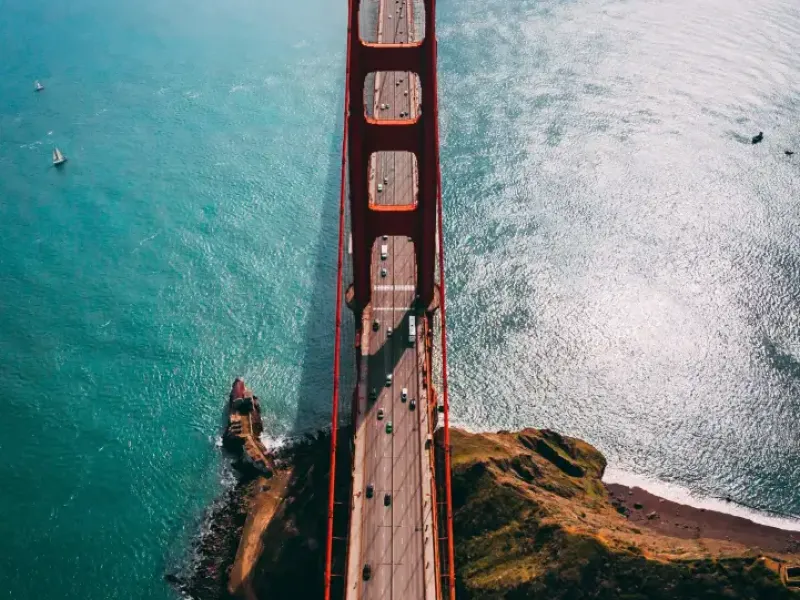 Aerial view looking down the Golden Gate Bridge in San Francisco; CA; with turquoise bay waters and light traffic below.