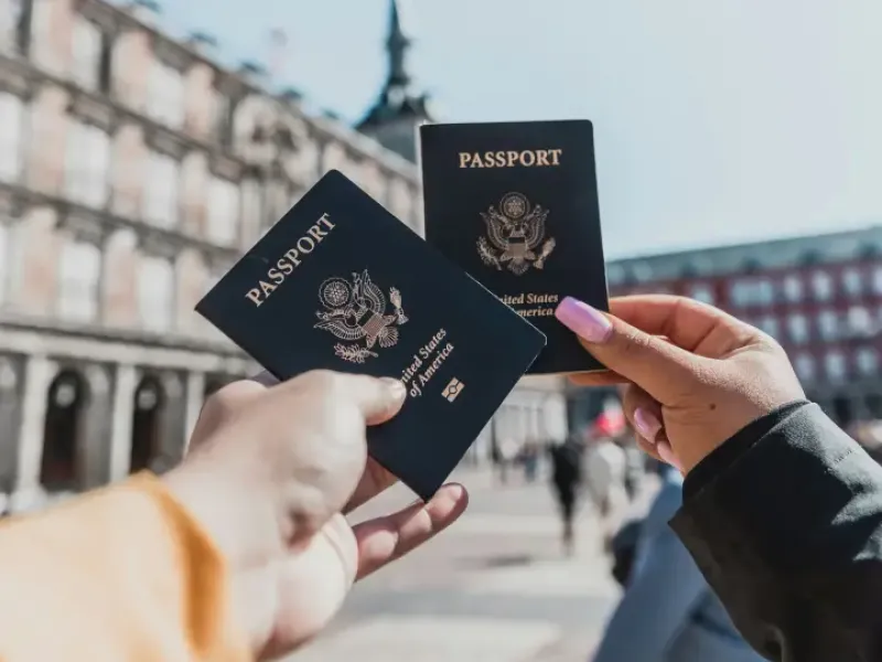 Two hands holding U.S. passports in a European plaza; symbolizing travel-support services for American travelers abroad.